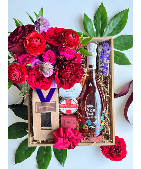self care gift crate with hot pink and red flowers, wine, bath bomb, balm, chocolates, and so much more