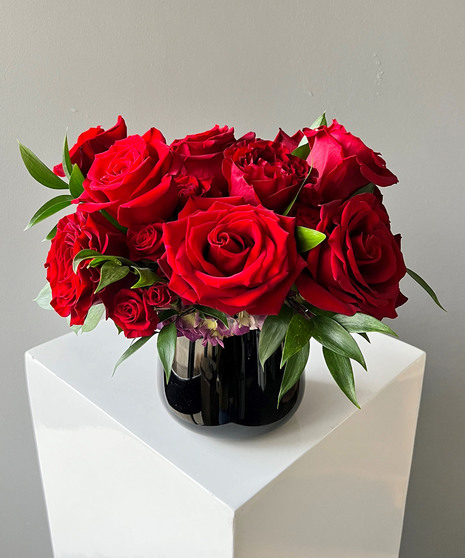 red rose arrangement in compact black vase
