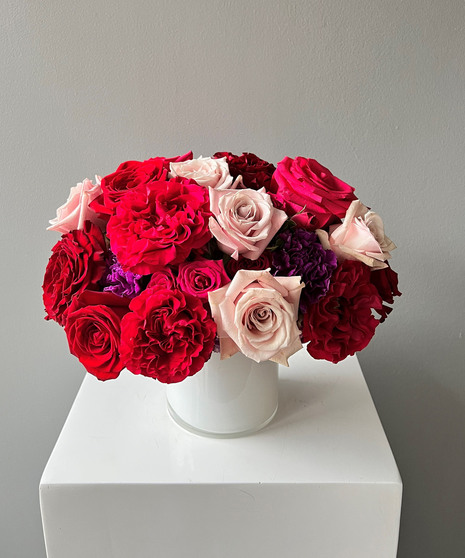 red, hot pink, and purple floral arrangement with roses and orchids